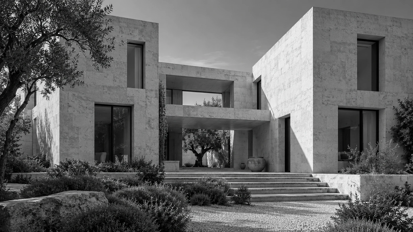 Pale limestone courtyard house with deep window openings and an olive tree