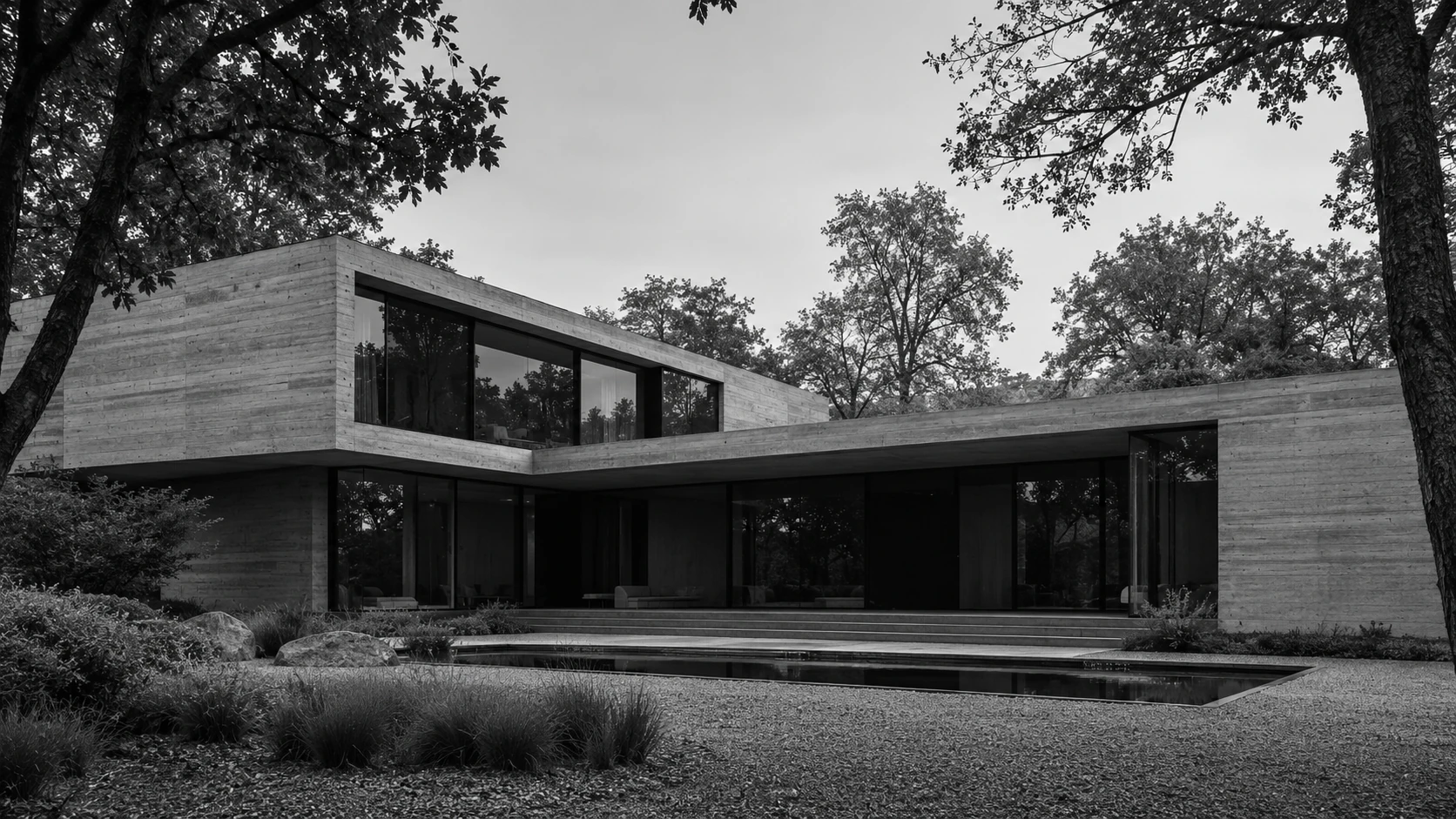 Concrete and glass courtyard home framed by trees and a reflecting pool